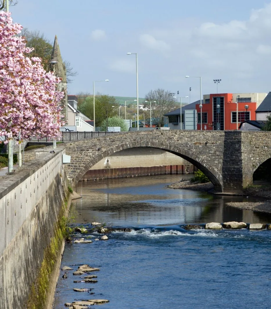 The old stone bridge over the river in Bridgend town centre, with blossom on the bank